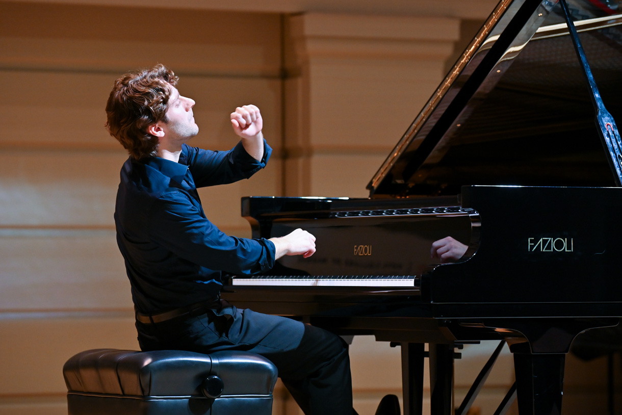 A male student playing the piano in a performance.